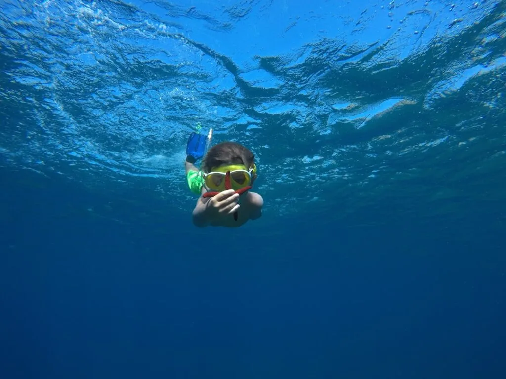 child snorkeling shallow water blue sea