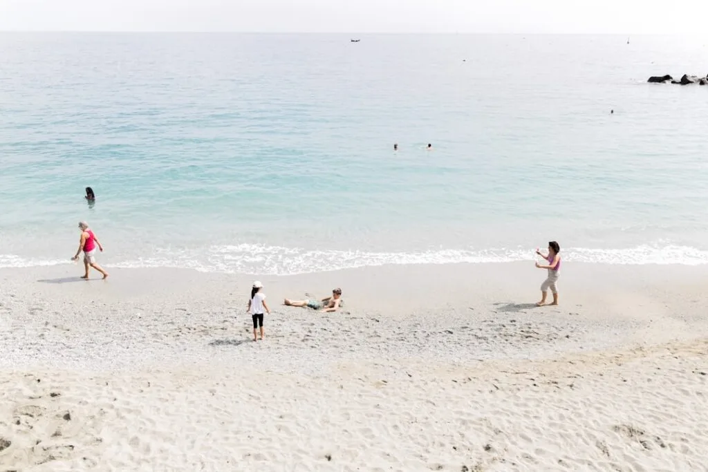 Gezinnen op kiezelstrand met turquoise zee in Monterosso, Cinque Terre