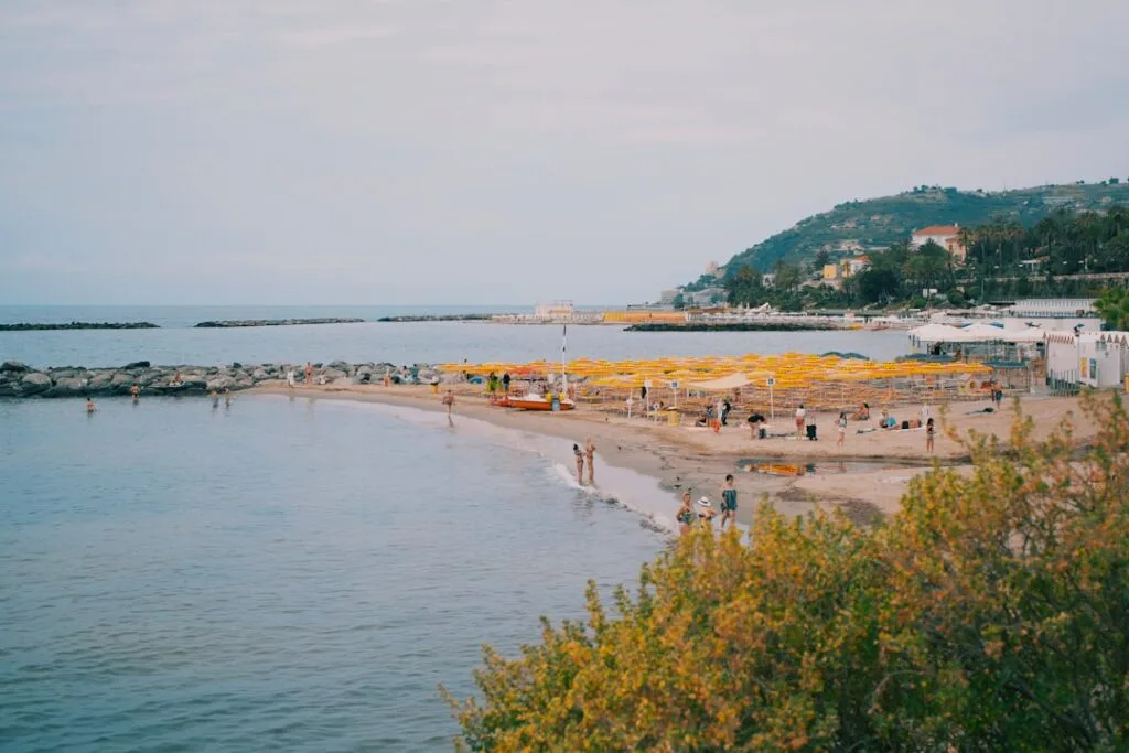 Plage bordée de parasols jaunes et baigneurs, côte des Cinque Terre