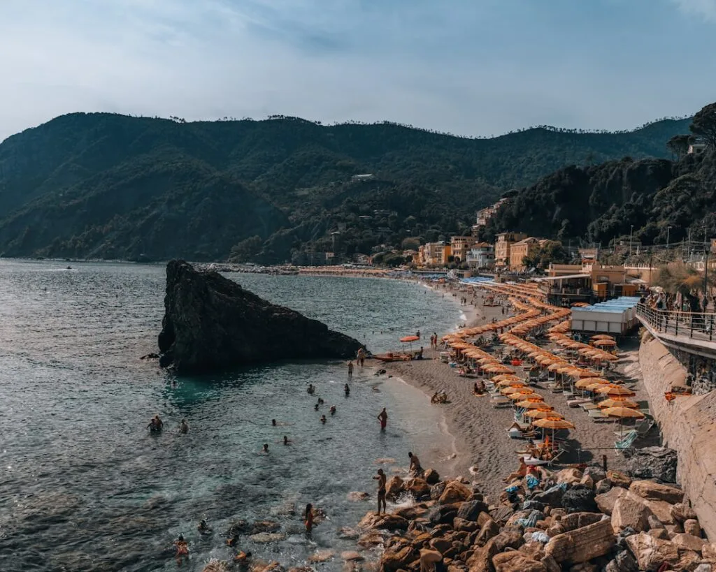 Plage de Monterosso avec alignements de parasols orange et nageurs