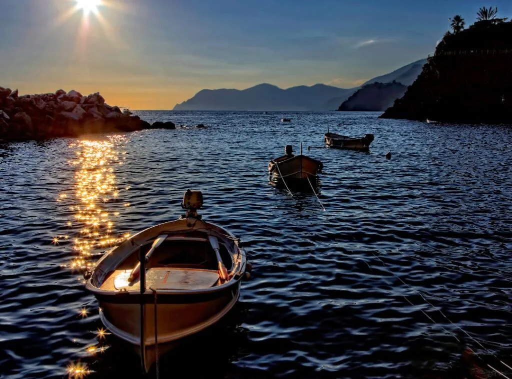 Gekleurde bootjes dobberen bij gouden zonreflecties in Cinque Terre