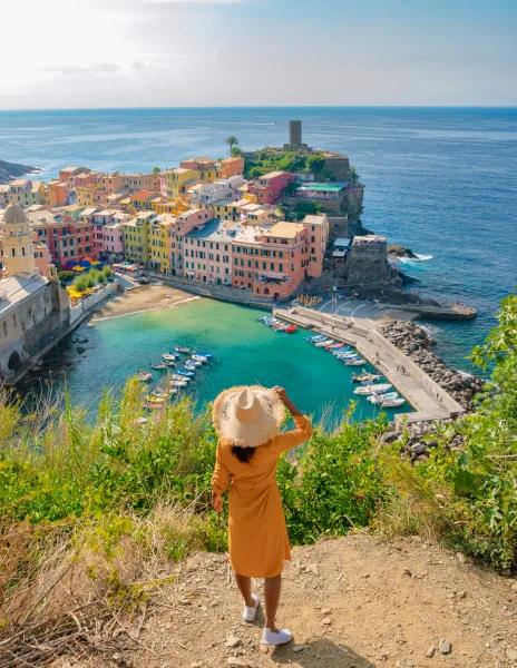 Femme en robe orange observant le port coloré de Vernazza, Cinque Terre