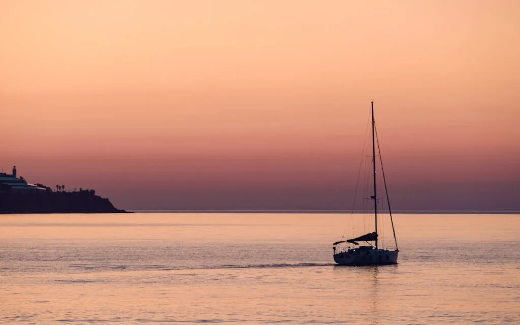 Voilier solitaire glissant au crépuscule devant la côte de Cinque Terre