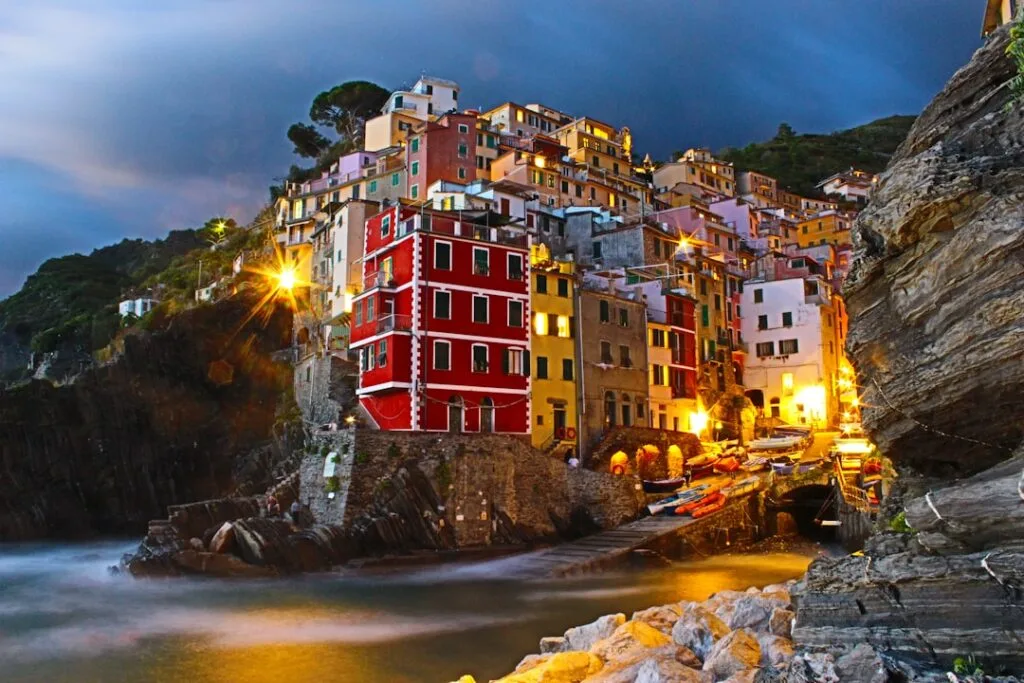 Felgekleurde huizen langs het haventje van Cinque Terre bij nacht