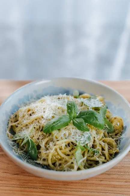 Bol de pâtes au pesto garni de basilic et parmesan râpé