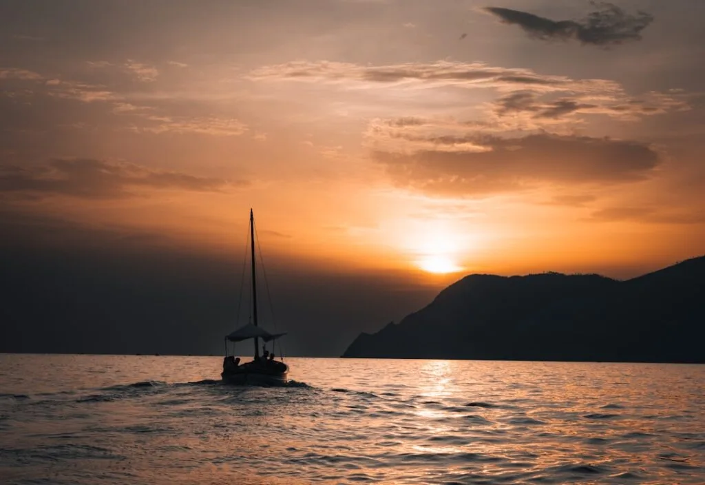 Voilier silhouetté au coucher de soleil devant la côte de Cinque Terre