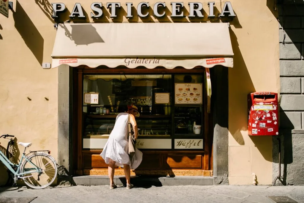Femme penchée au comptoir d'une gelateria sous l'enseigne Pasticceria