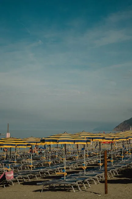 Rangées de parasols rayés jaunes et bleus sur une plage des Cinque Terre
