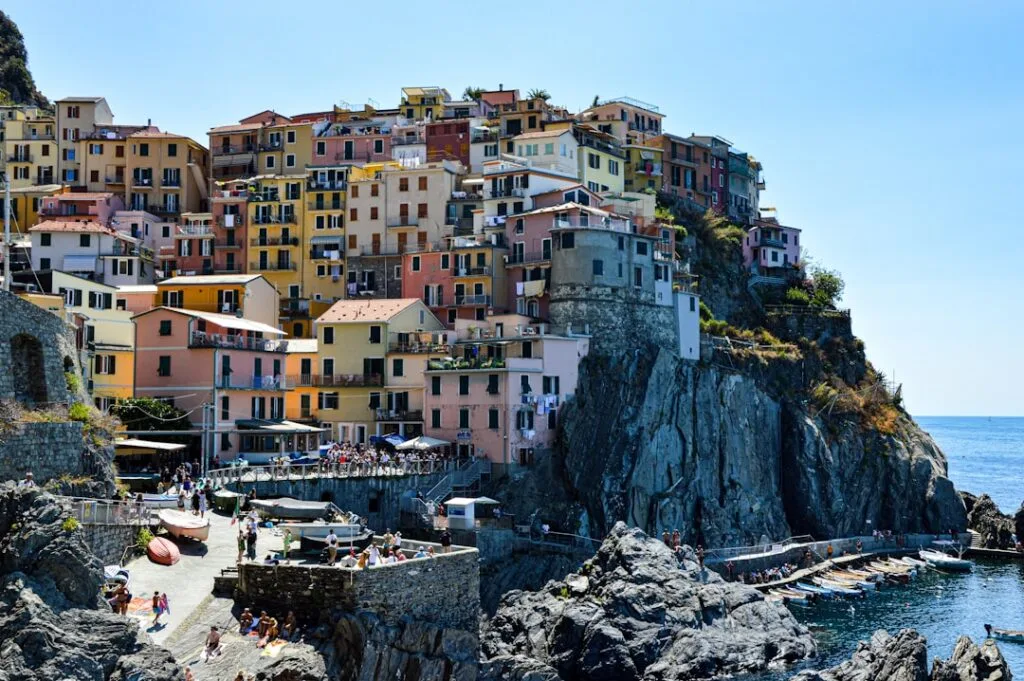 Façades pastel agglutinées sur la falaise, crique et bateaux des Cinque Terre