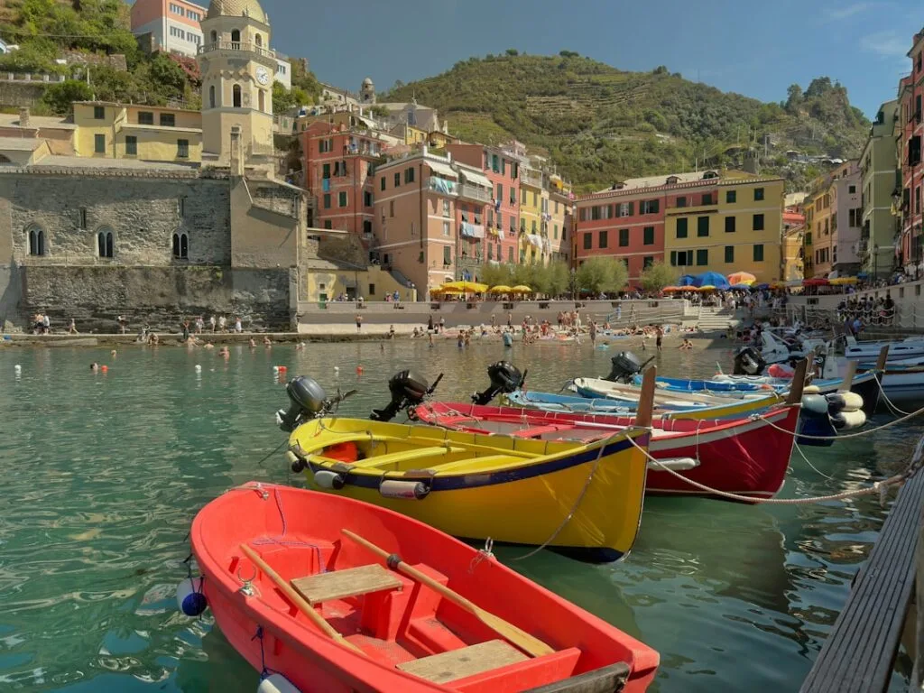 Barques colorées amarrées dans le port animé des Cinque Terre, maisons pastel.