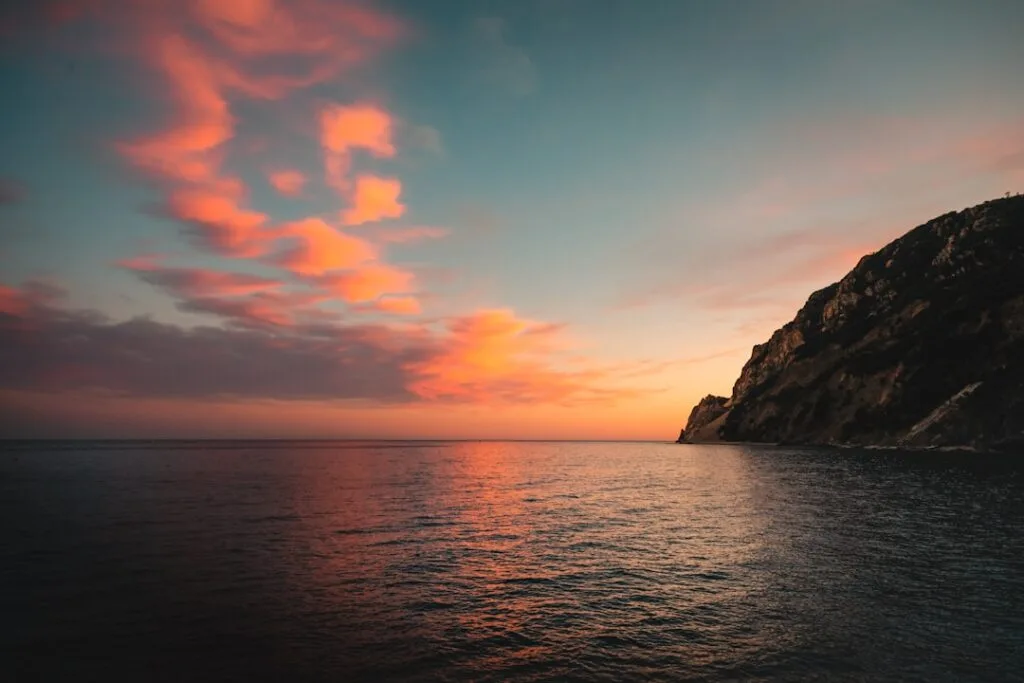 Nuages roses au coucher, mer calme et falaise escarpée près des Cinque Terre